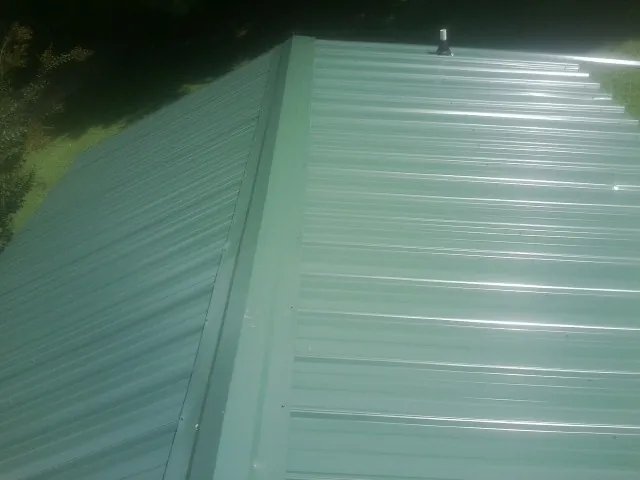 New green metal panels meeting at the ridge of a roof — Flat Roof Repair work by our crew in Saint Simons Island