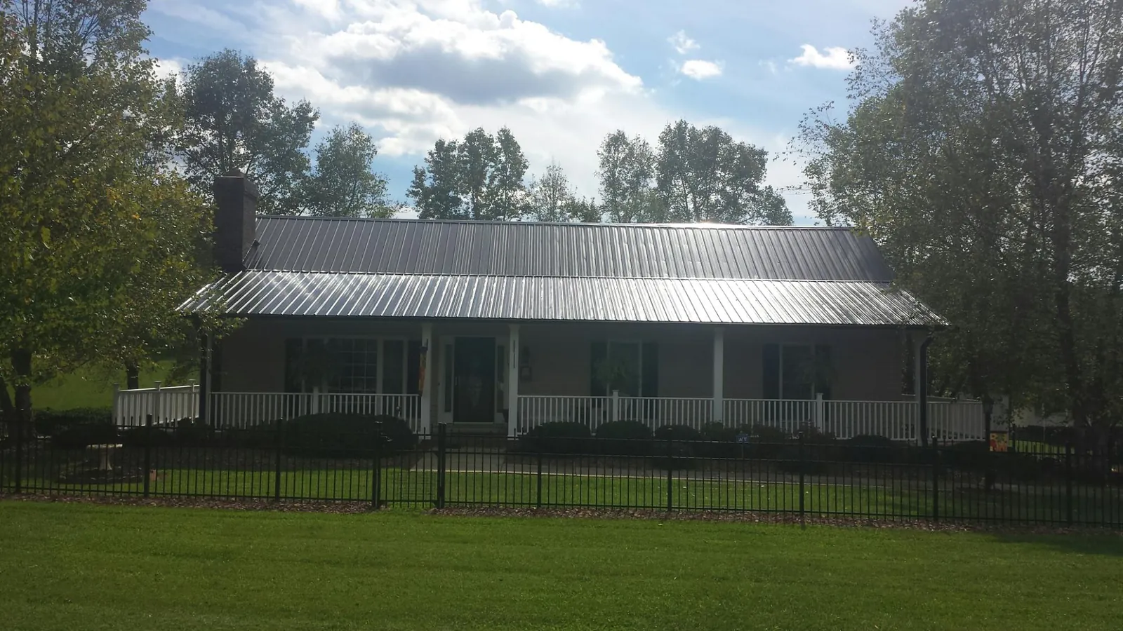 Gray metal roof on a brick ranch with a full width front porch — Gutter Guard Installation work by our crew in Saint Simons Island