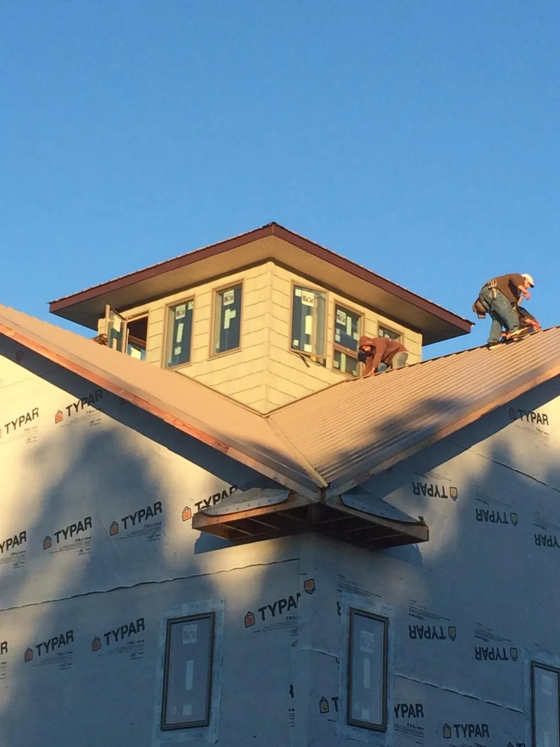Roofers working around a rooftop cupola on a new metal roof at sunset — Roof Waterproofing in Saint Simons Island by Roofing Brothers